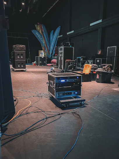 Backstage moment with a DJ preparing for a set, cables and equipment in soft focus.