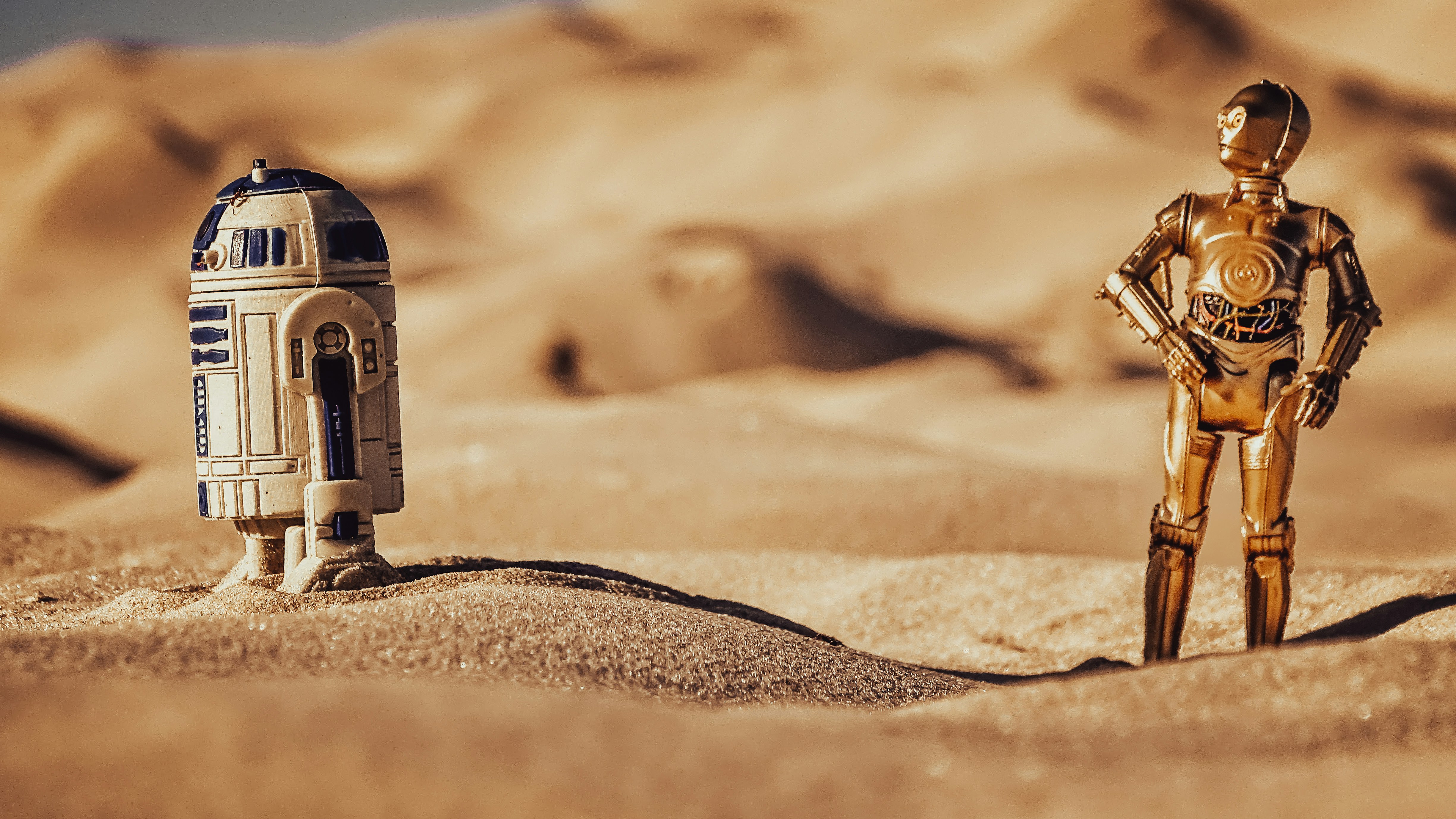 A model recreation of a scene from Star Wars: A New Hope. C-3PO has stopped to talk to R2-D2 on desert landscape