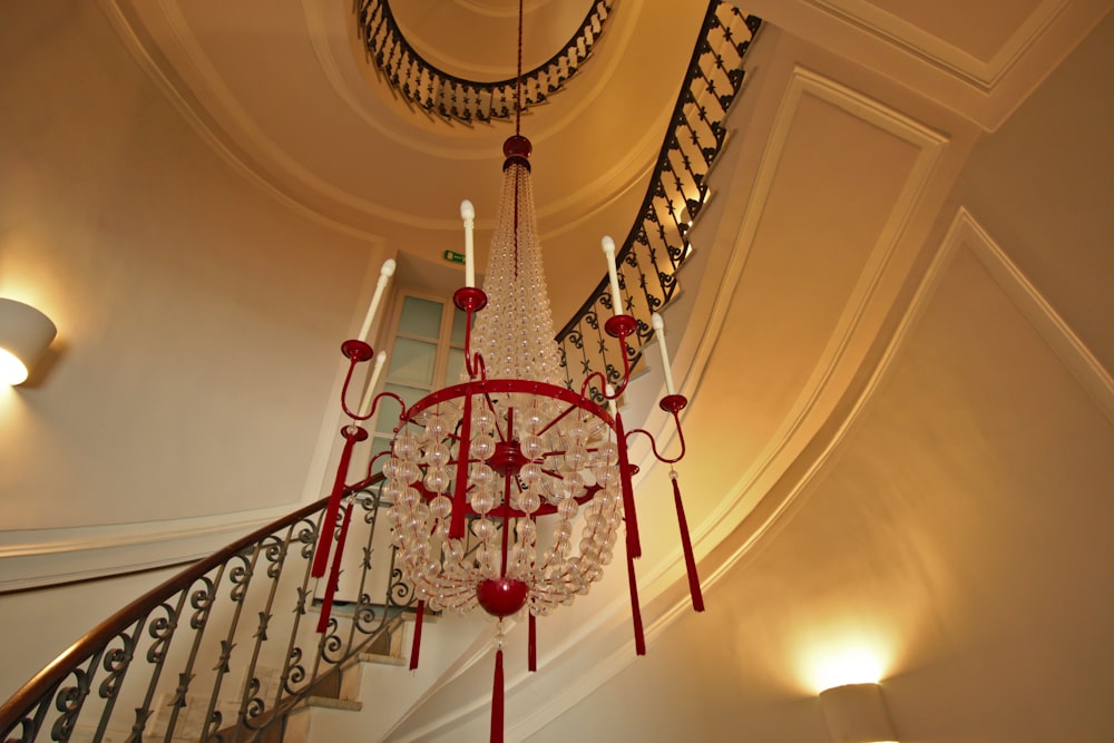 a staircase with a red and white railing and a chandelier