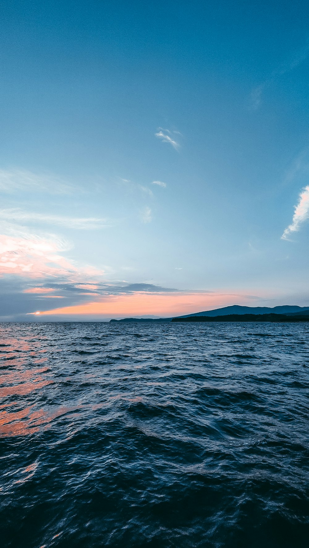 un cuerpo de agua con un cielo azul y nubes