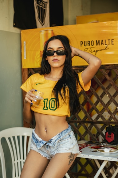 a person sitting on a chair holding a drink and posing for the camera