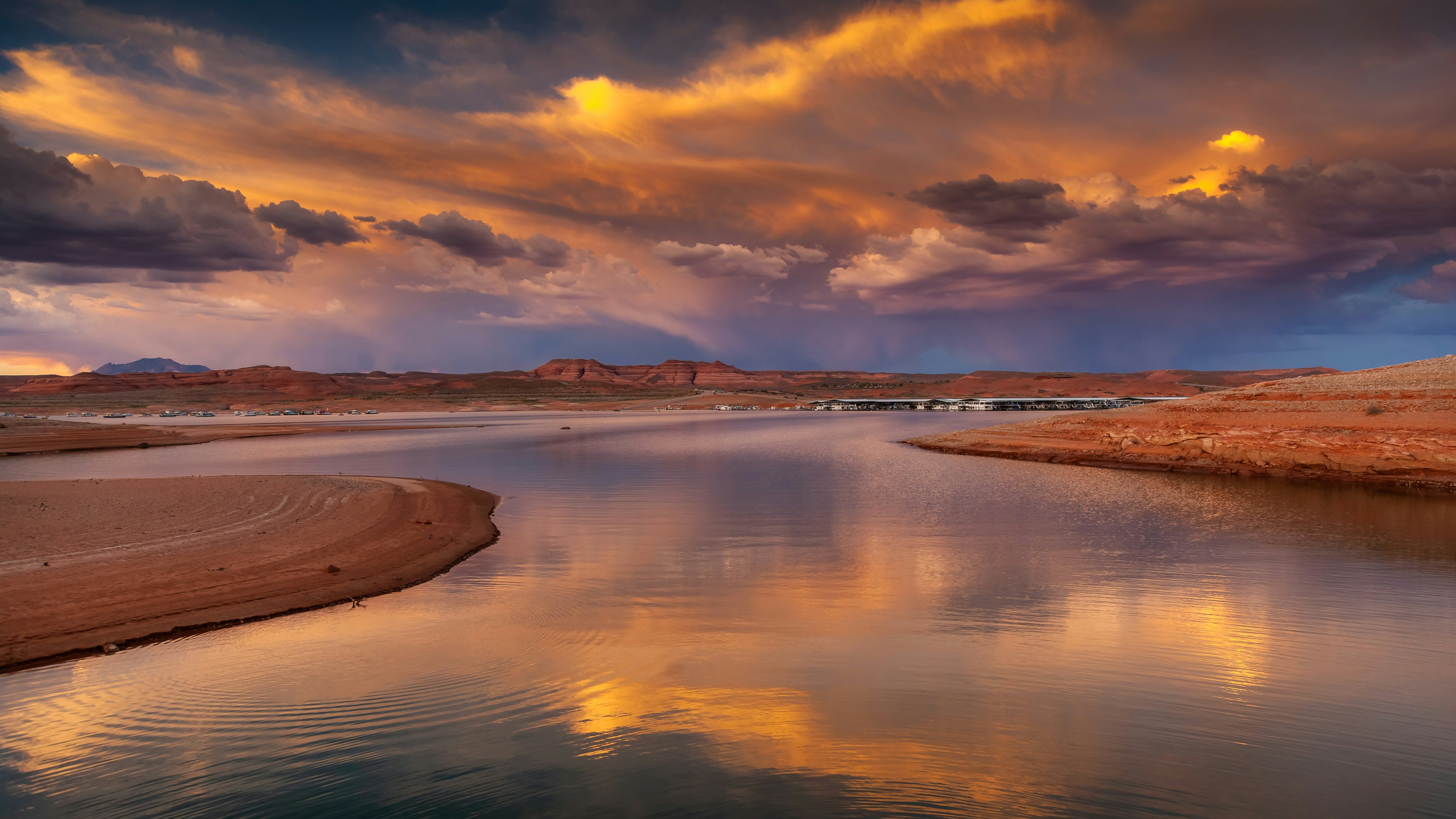 a body of water with a sandy beach and mountains in the background