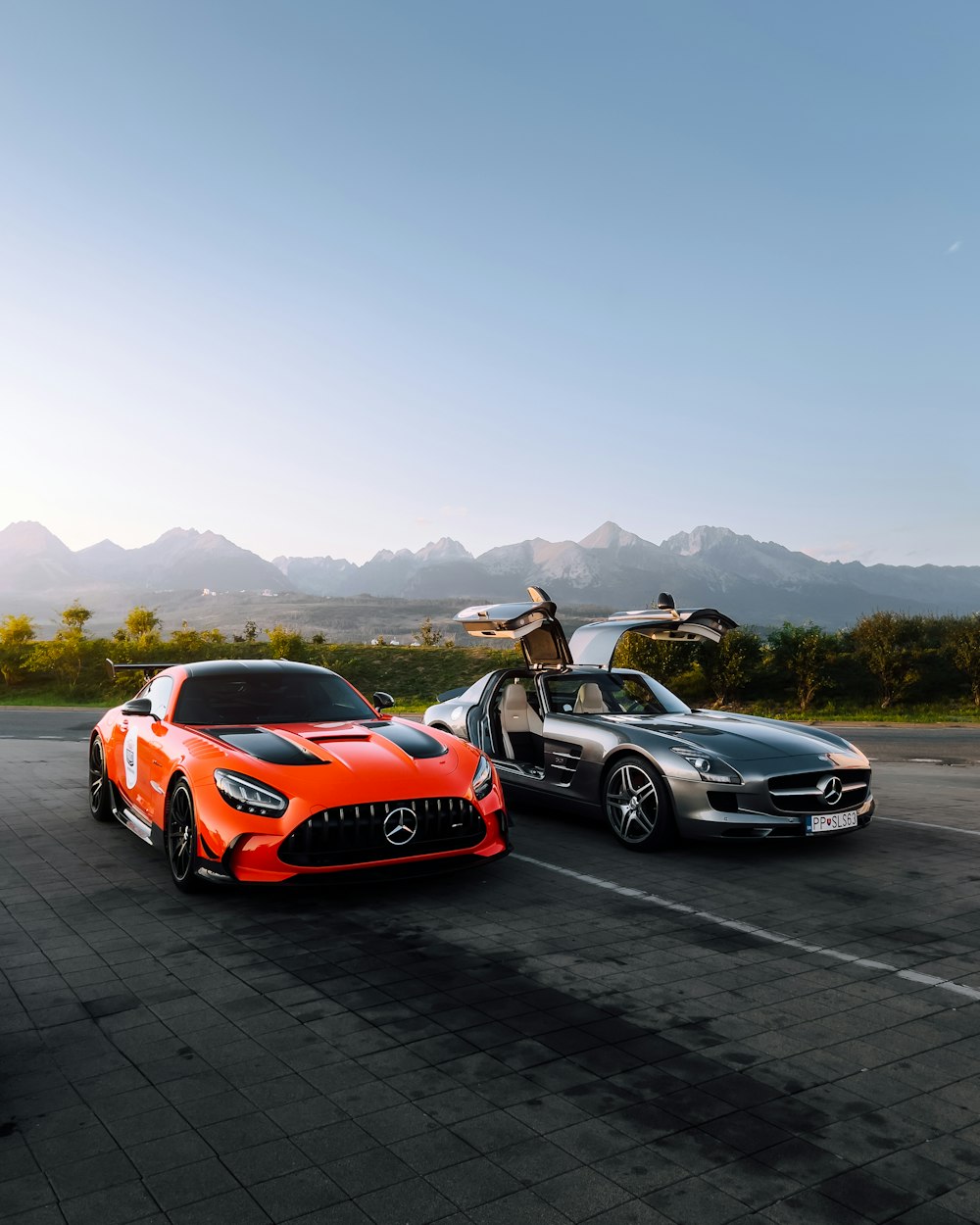 a group of cars parked in a parking lot with mountains in the background