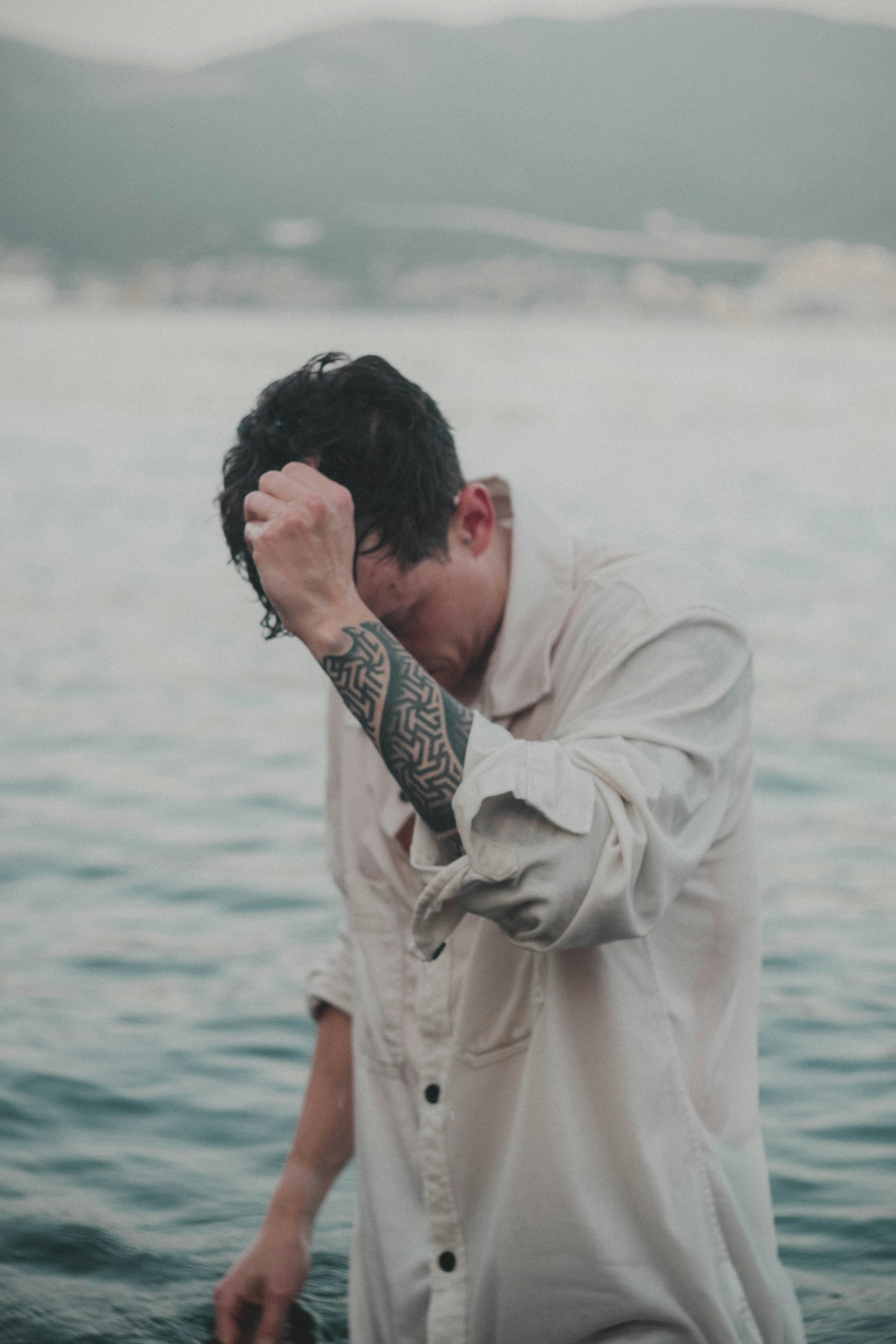 a man with his hand on his face looking at the water