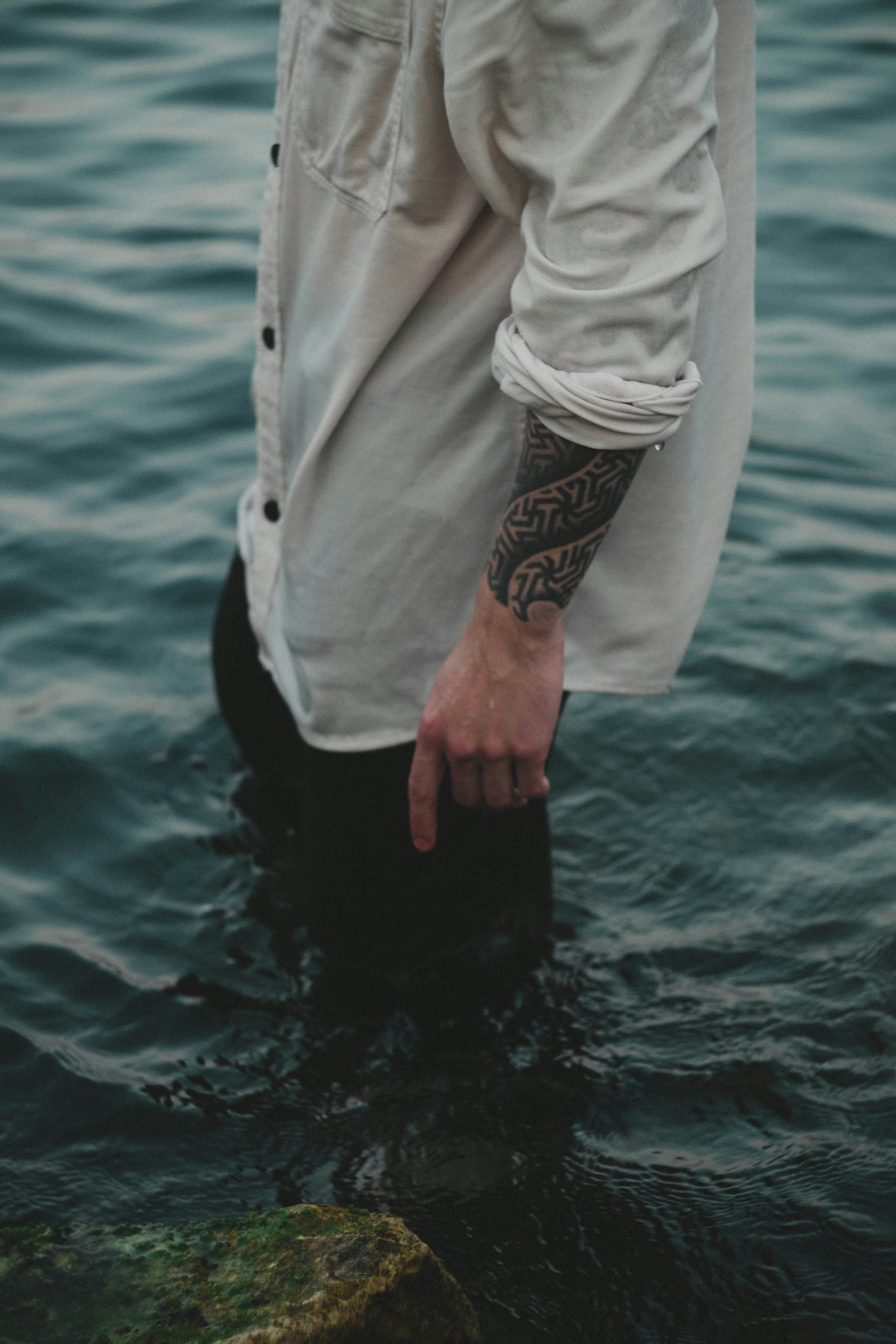 a person in a white coat and black pants standing in water