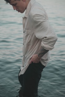 a man wearing a white shirt and black pants with a tattoo on his arm