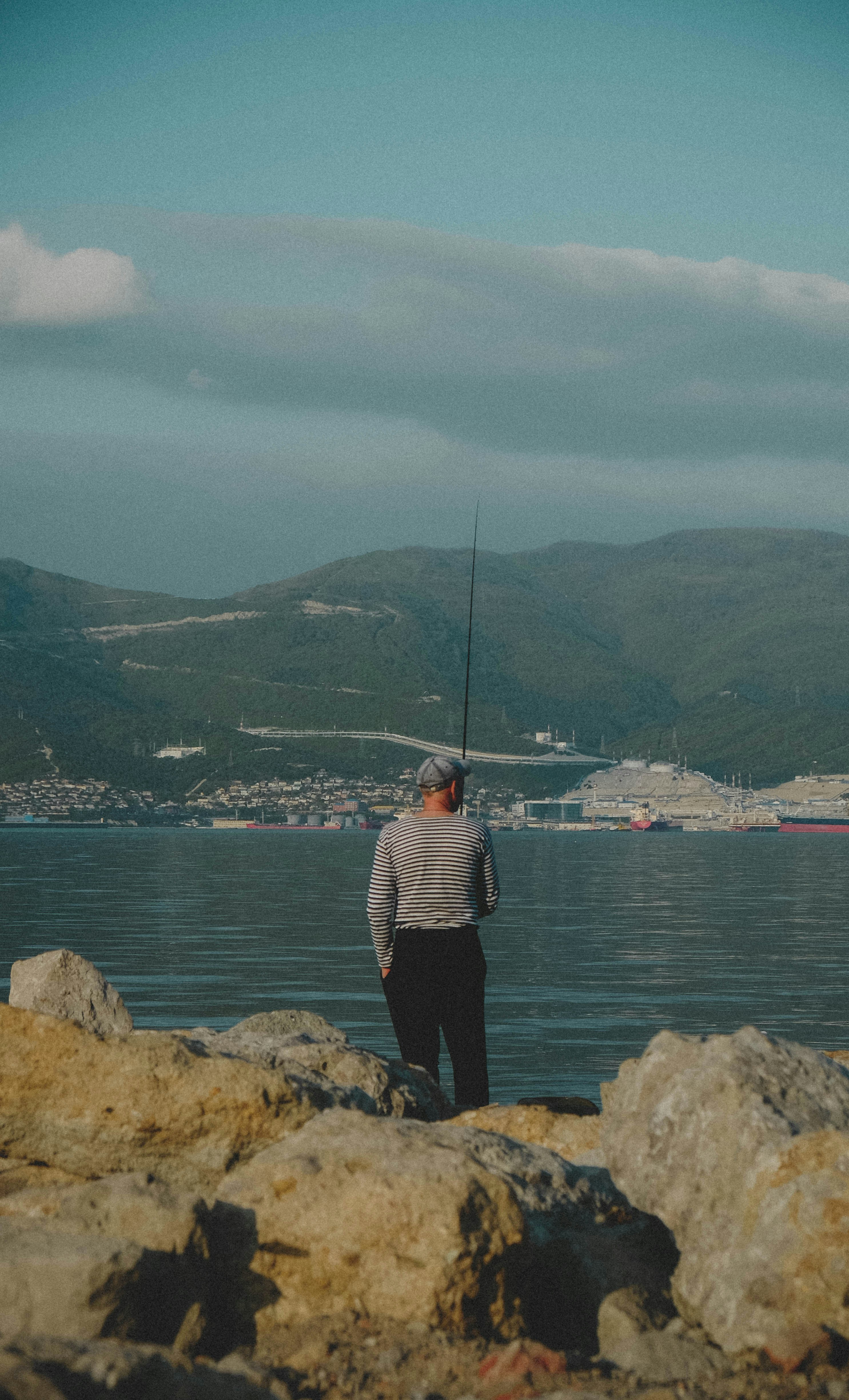 a man standing on a rock looking at a fishing pole