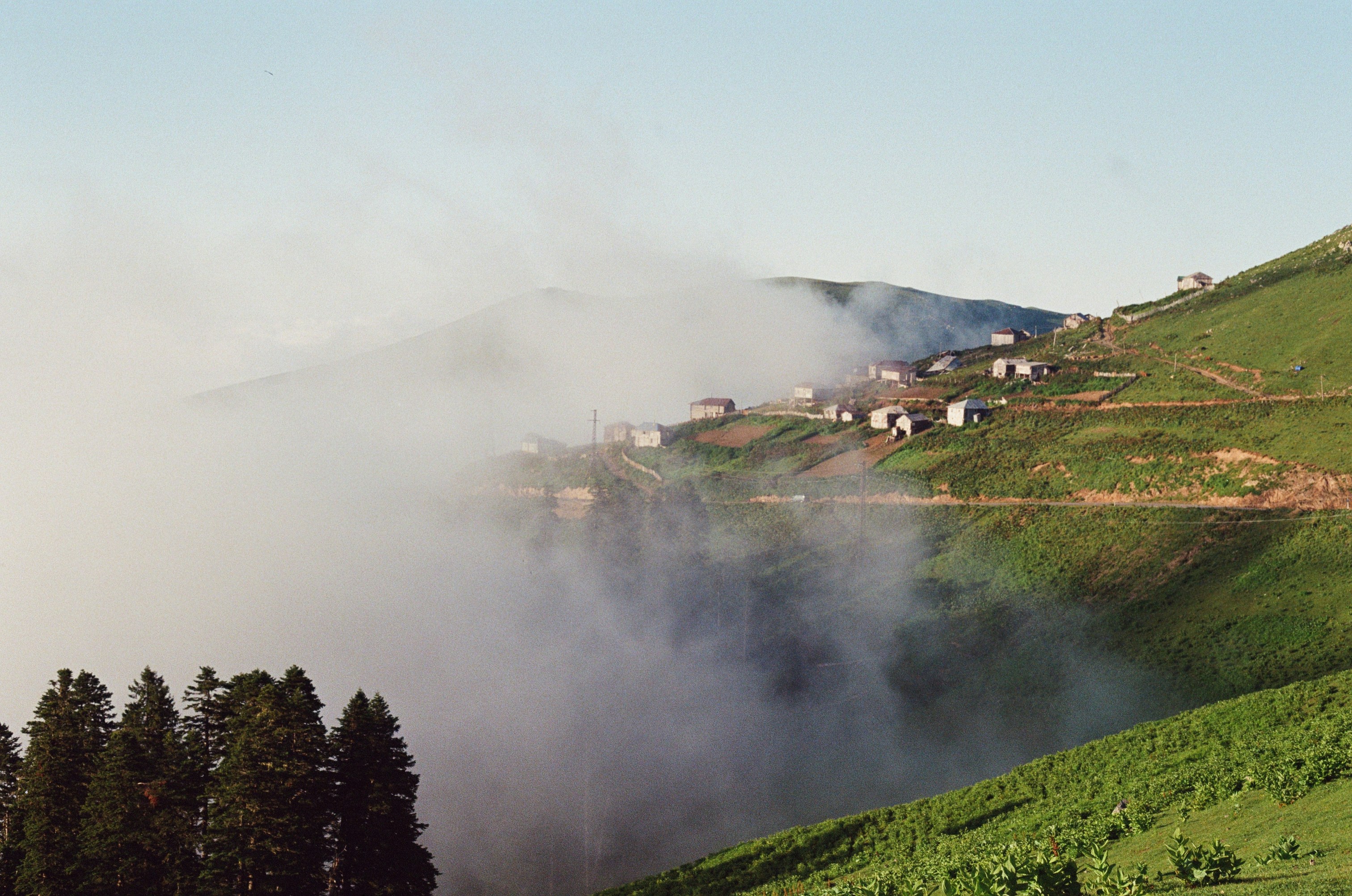a foggy valley with houses and trees