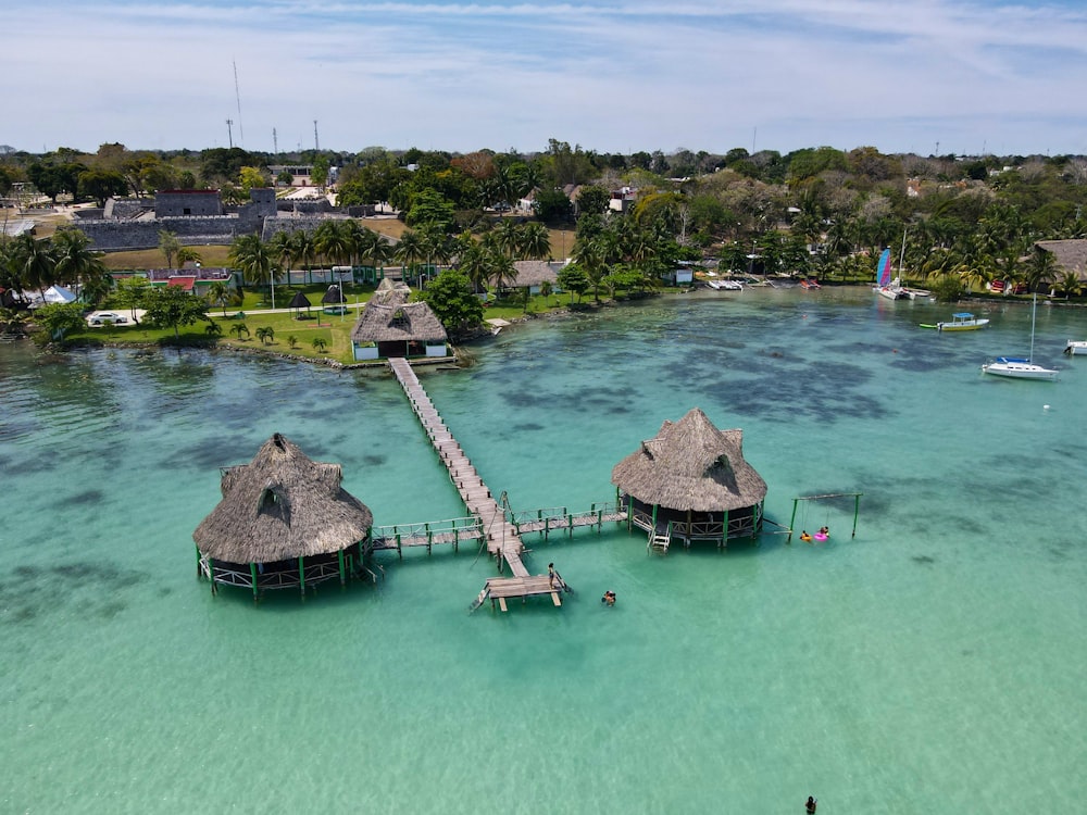 a group of huts on a dock over a body of water with Xelha in the background