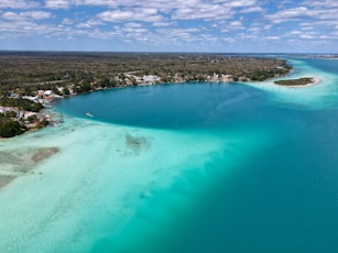 a large body of water with a beach and houses in the background