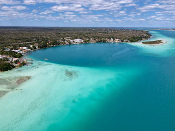 a large body of water with a beach and houses in the background