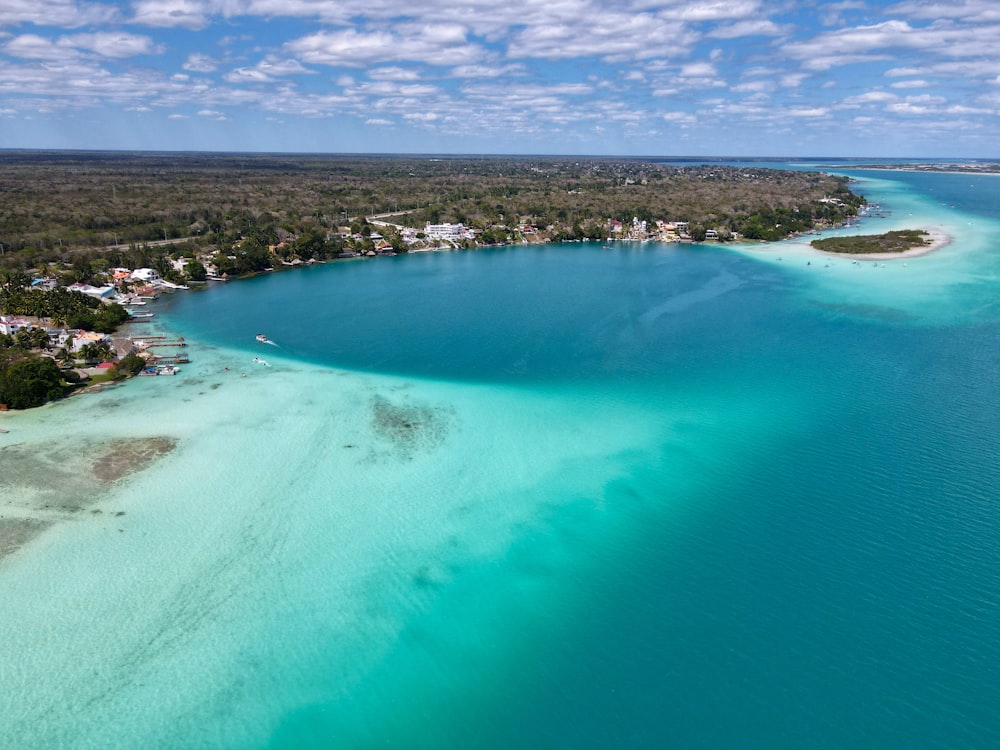 a large body of water with a beach and houses in the background