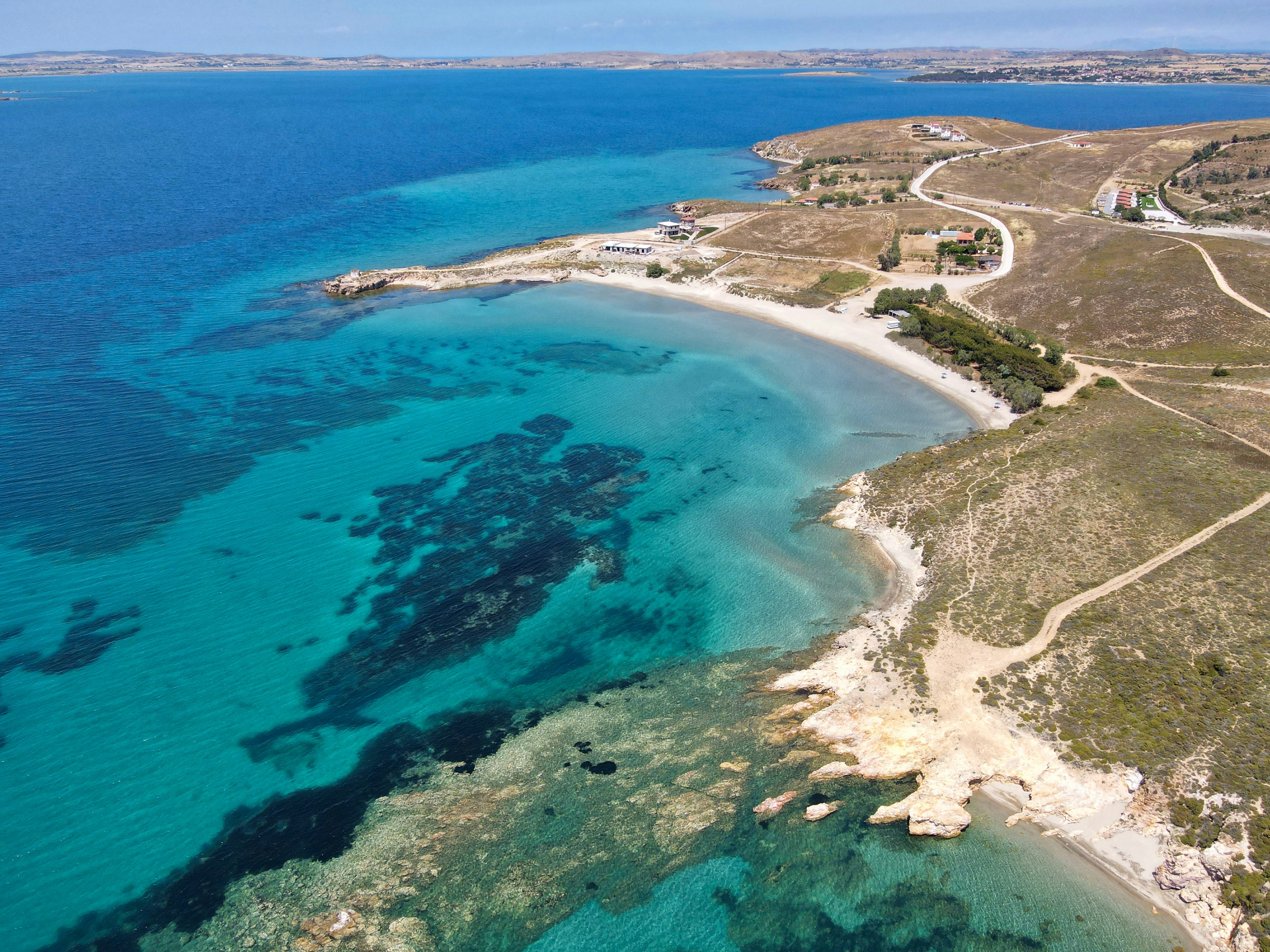 an aerial view of a beach and ocean, A view from above, shot at Fanaraki beach a beach located at Lemnos island in northeastern Aegean sea, Greece.