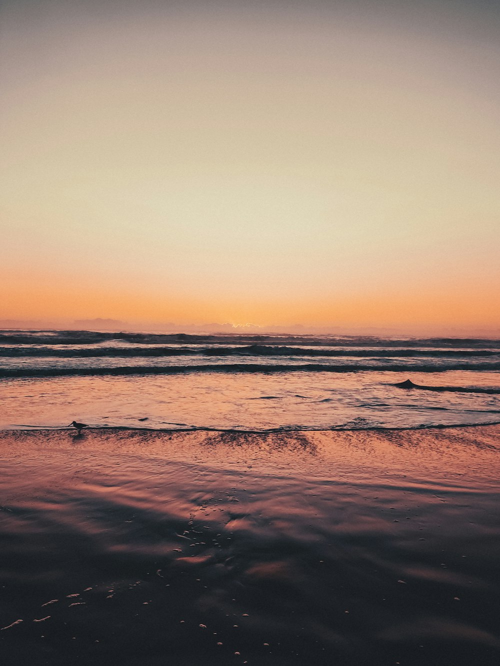 a beach with waves and a sunset