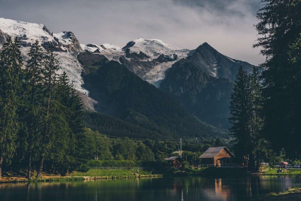 Una casa junto a un lago con montañas al fondo