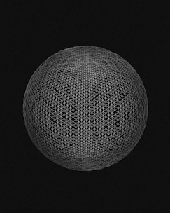 A geometric sphere composed of intersecting thin white lines forms a mesh pattern against a black background. The lines create a symmetrical, grid-like structure with a sense of depth and dimensionality.