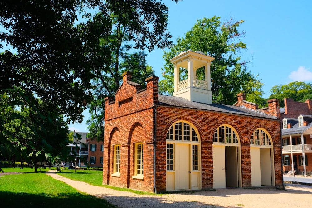 a brick building with a bell tower with Fort Christian in the background