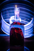 Dynamic shot of Tizerpacaps bottle glowing with purple and gold light beams on a sleek black background.