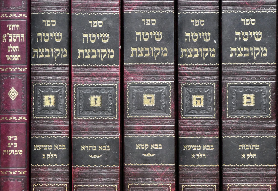 A row of bound Hebrew sefarim on a shelf