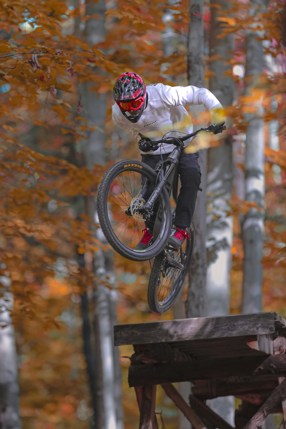 a person on a bike jumping over a wooden railing
