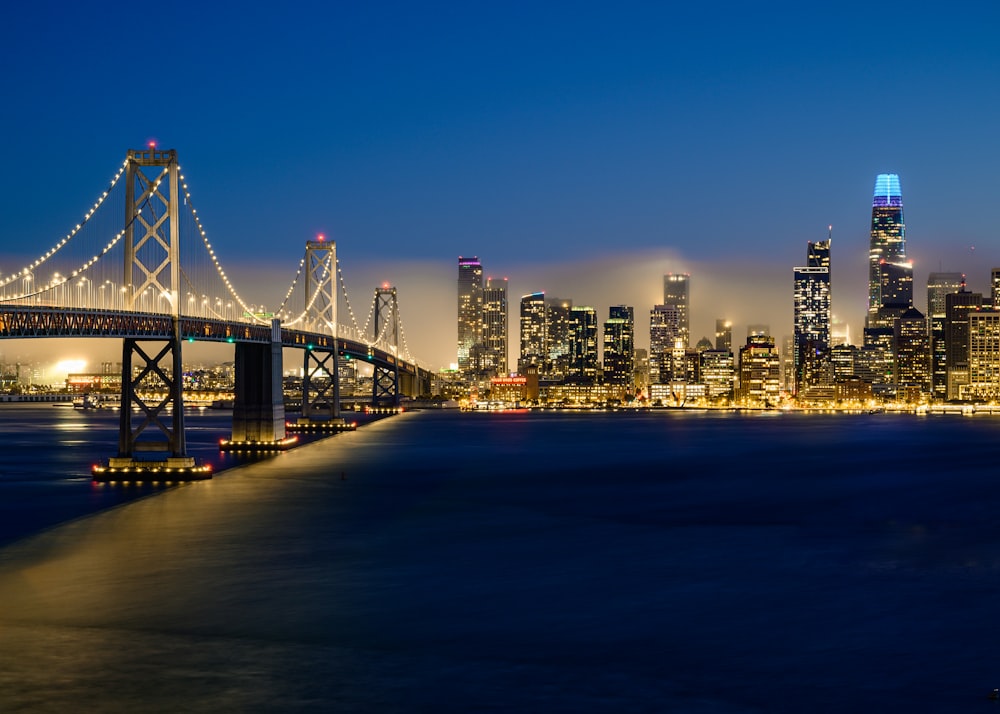 a bridge over a body of water with a city in the background