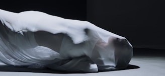 A model draped in a flowing garment made from lightweight fabric.