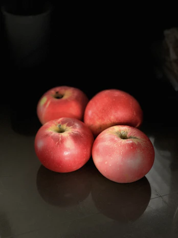 Golden apples glistening under soft light, highlighting their smooth texture and rich color.