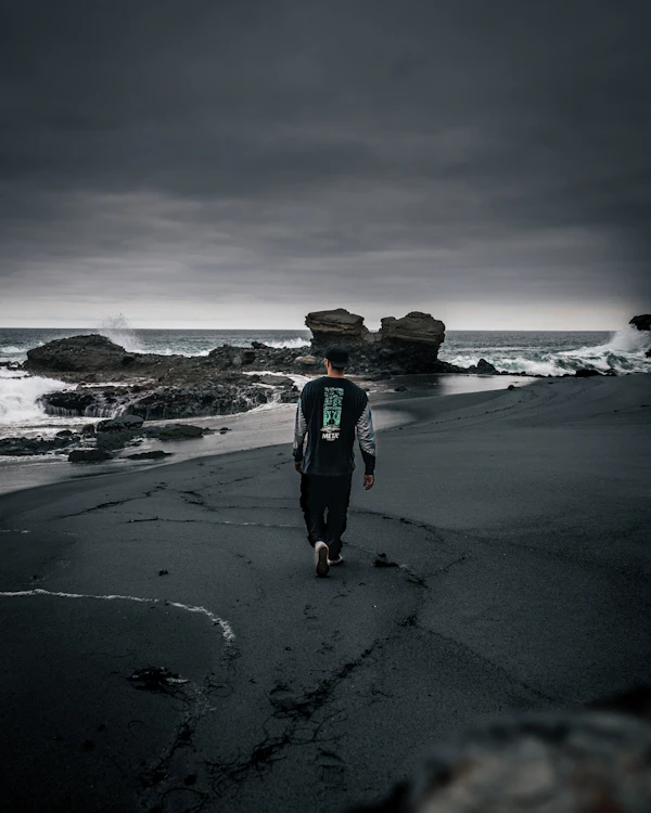 Figura solitaria en playa moody — vibe costanero