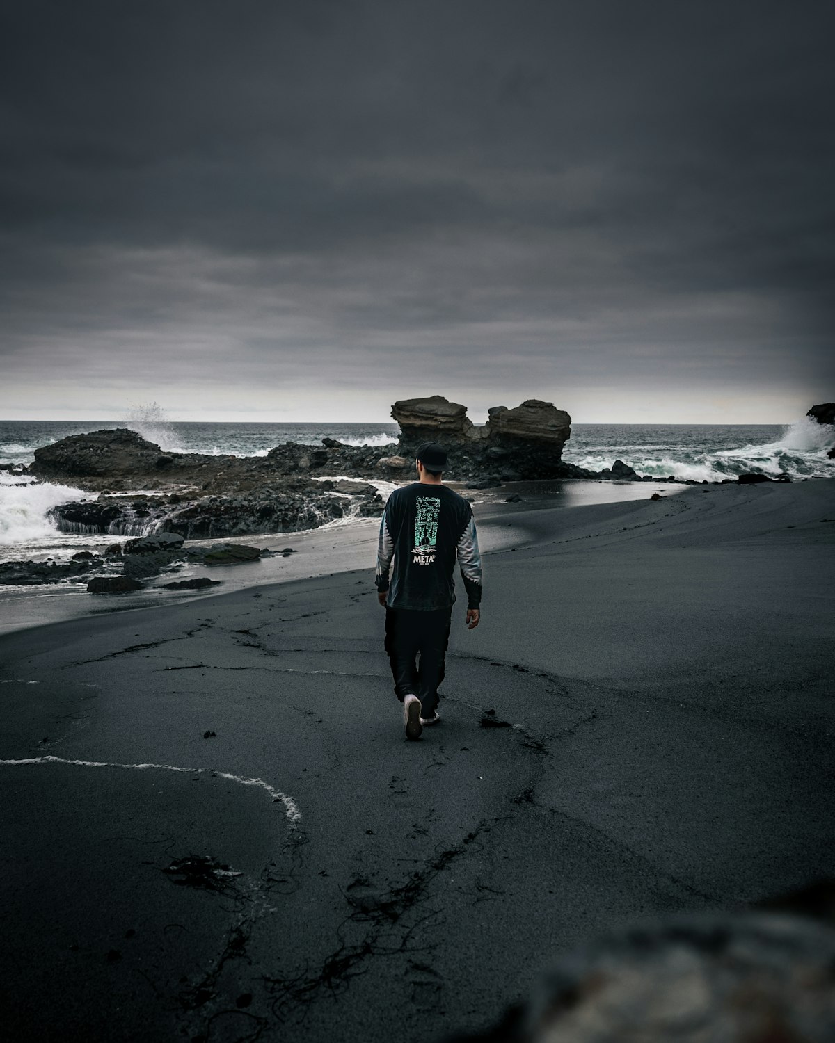 A person walking alone on a moody beach, taking the first steps forward