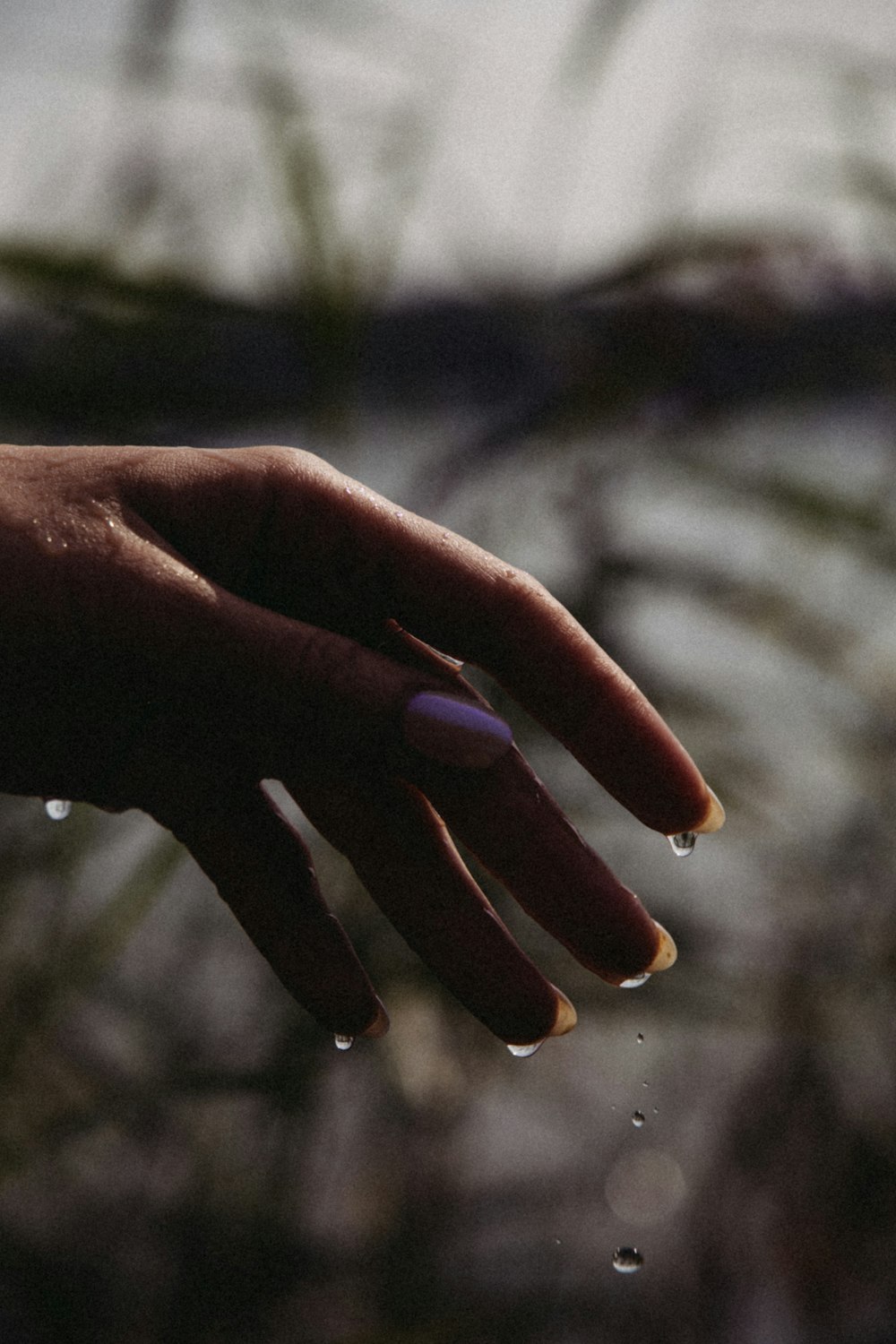 a hand holding a small water droplet
