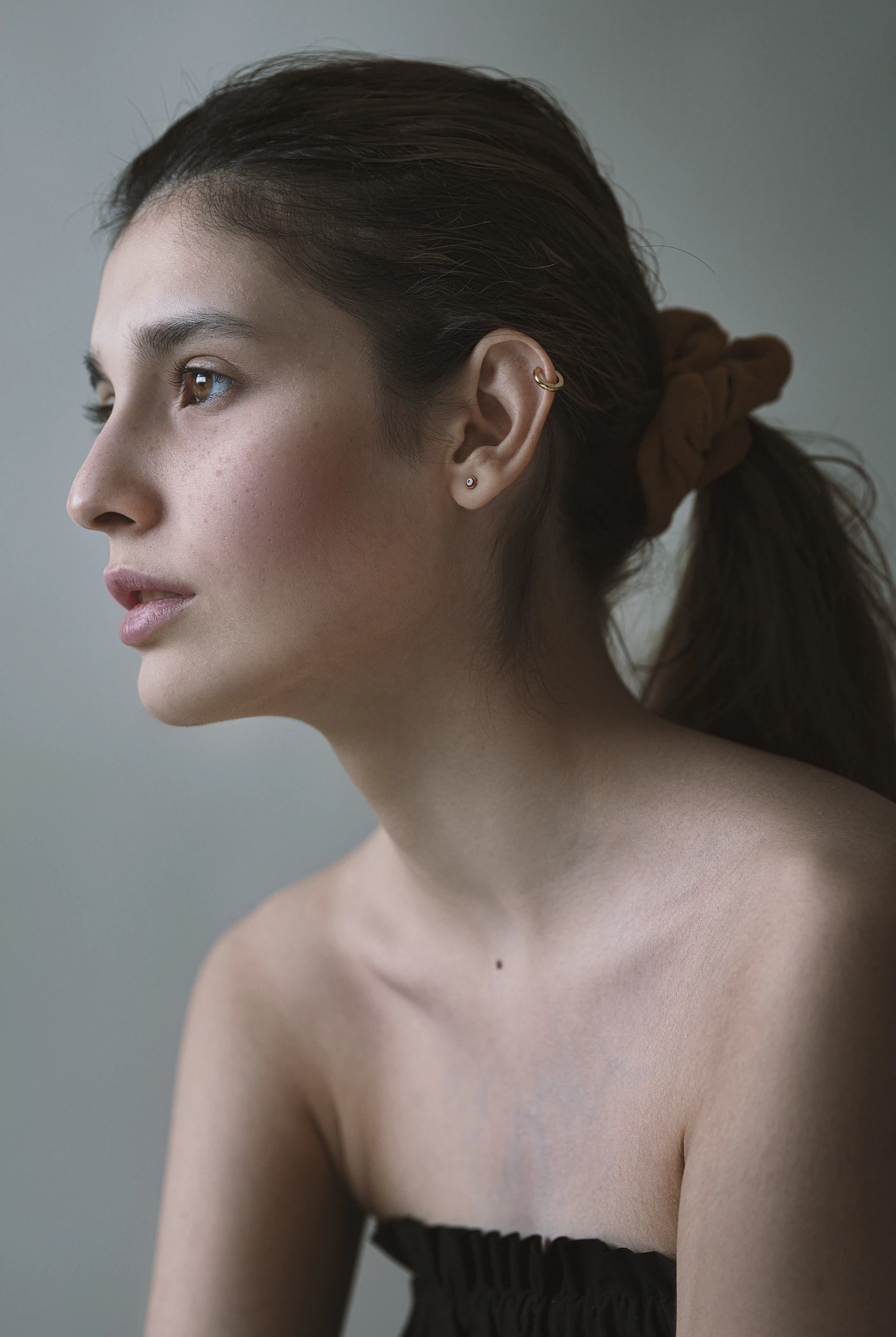 Close-up three-quarter portrait of a woman showing a defined jawline, chin and neck profile against a neutral background, representing the treatment area for V-line contouring injection