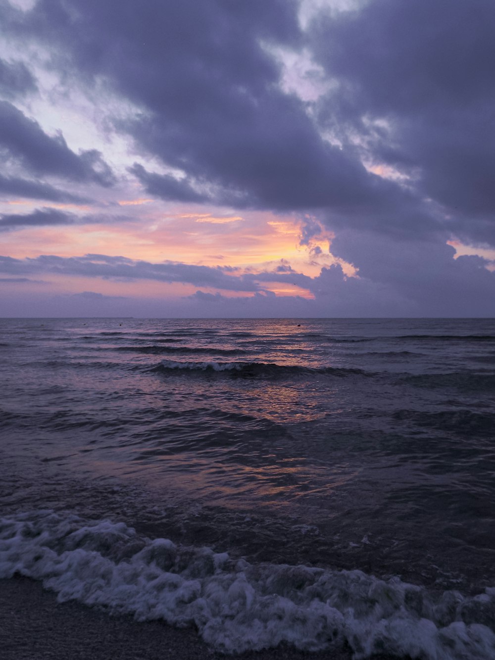 a body of water with waves and clouds in the sky