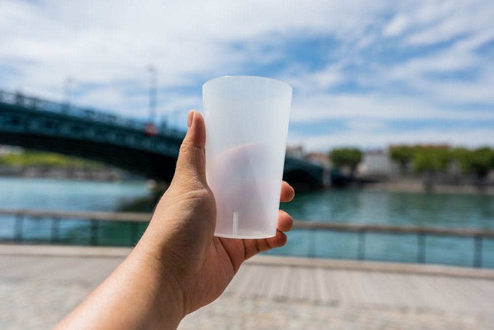 a hand holding a white cup