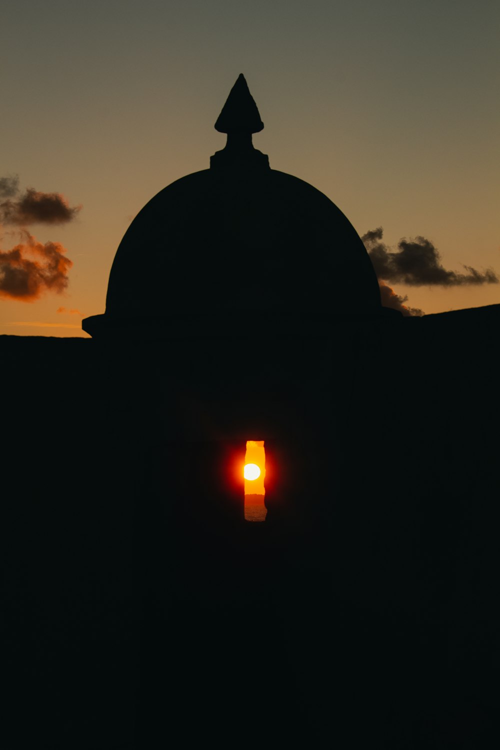 a silhouette of a dome with a sunset in the background