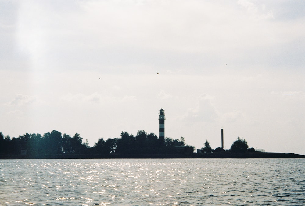 a body of water with trees and a tower in the distance