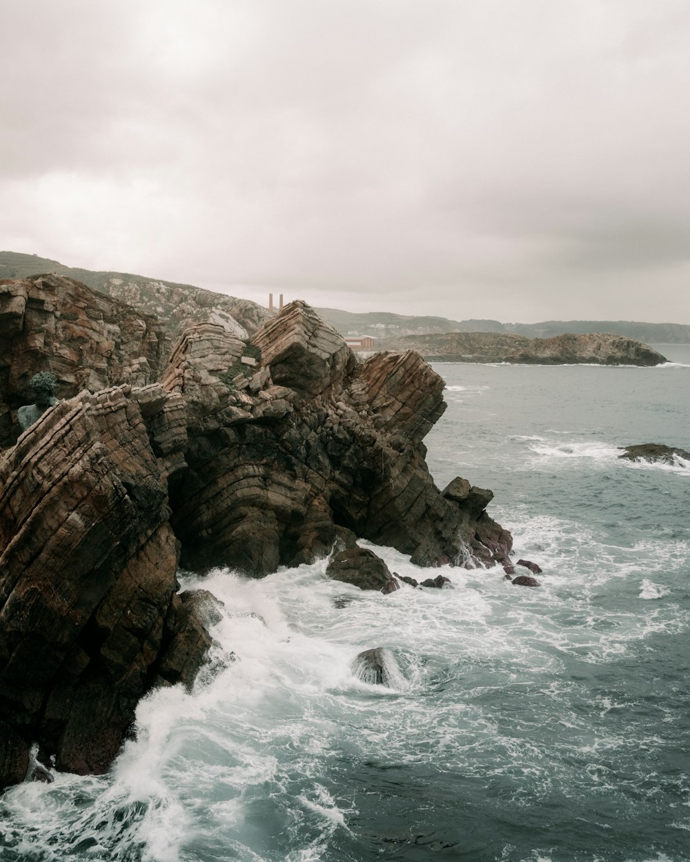 a rocky cliff with waves crashing against it