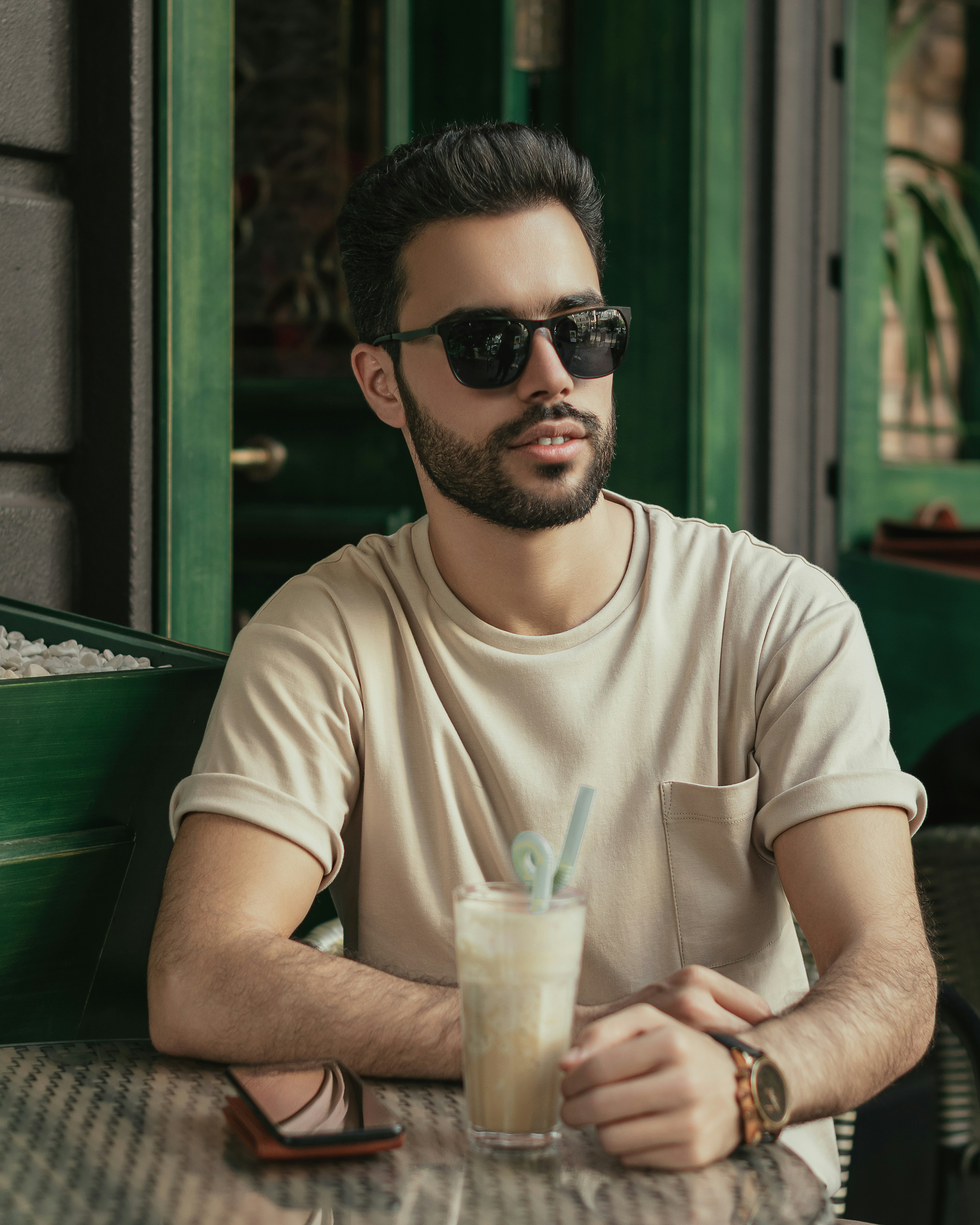 a man wearing sunglasses and holding a drink