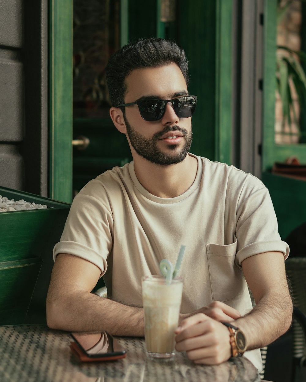 a man wearing sunglasses and holding a drink