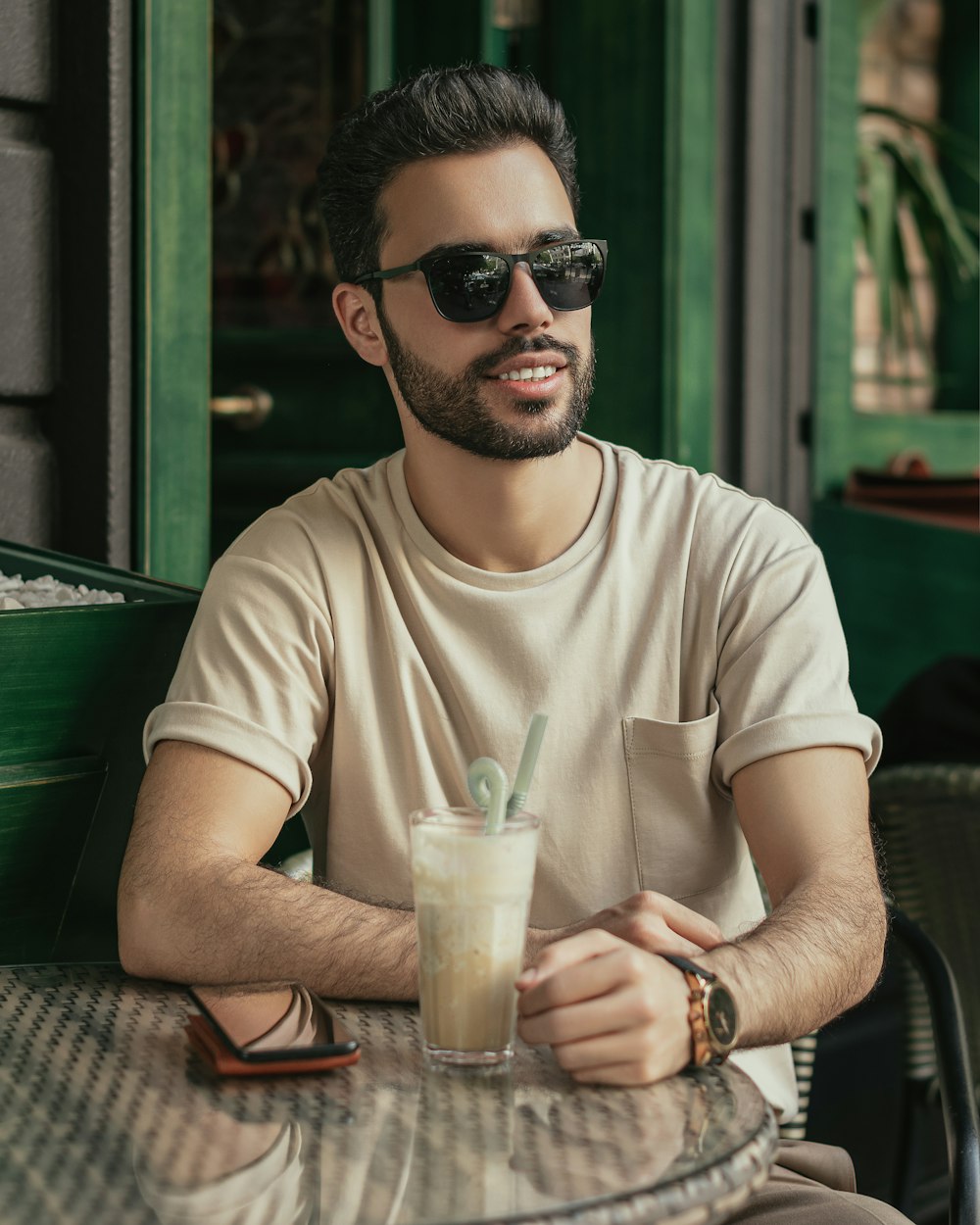 a man wearing sunglasses and holding a drink