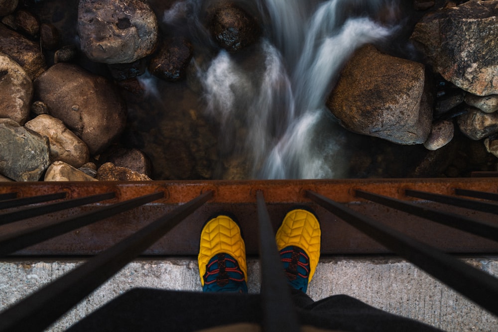 a pair of yellow shoes on a wooden bench in front of a waterfall