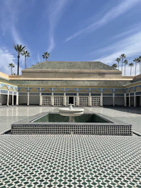 Elegant Moroccan riad courtyard with zellige tiles and palm trees under warm sunlight.