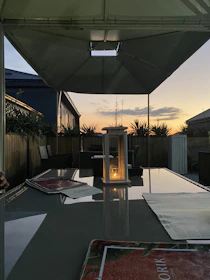 A serene backyard patio featuring neutral-toned furniture and soft glowing lights at dusk.