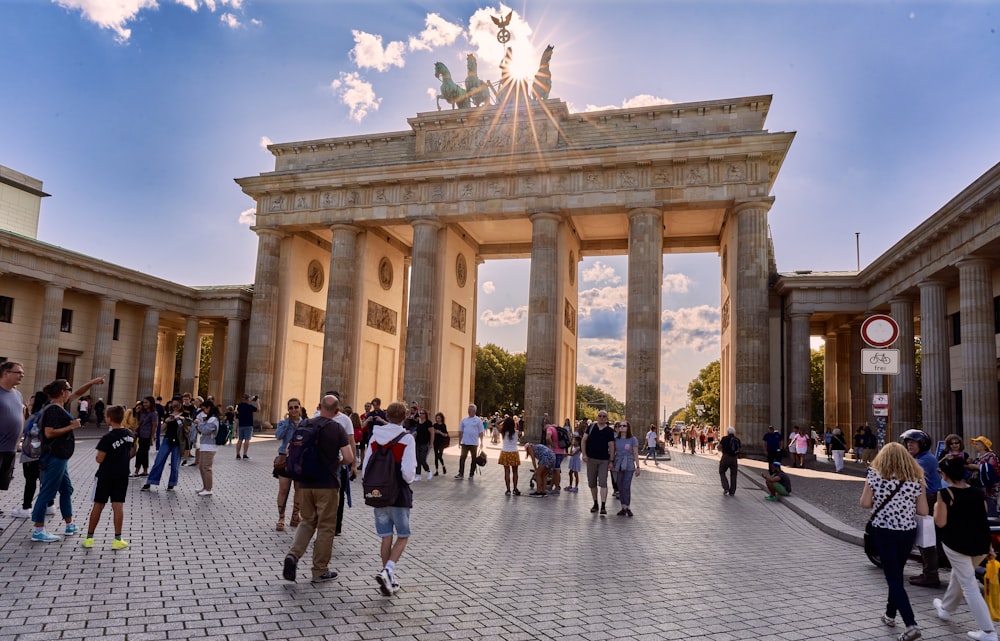un gran grupo de personas caminando alrededor de la Puerta de Brandenburgo con una estatua en la parte superior