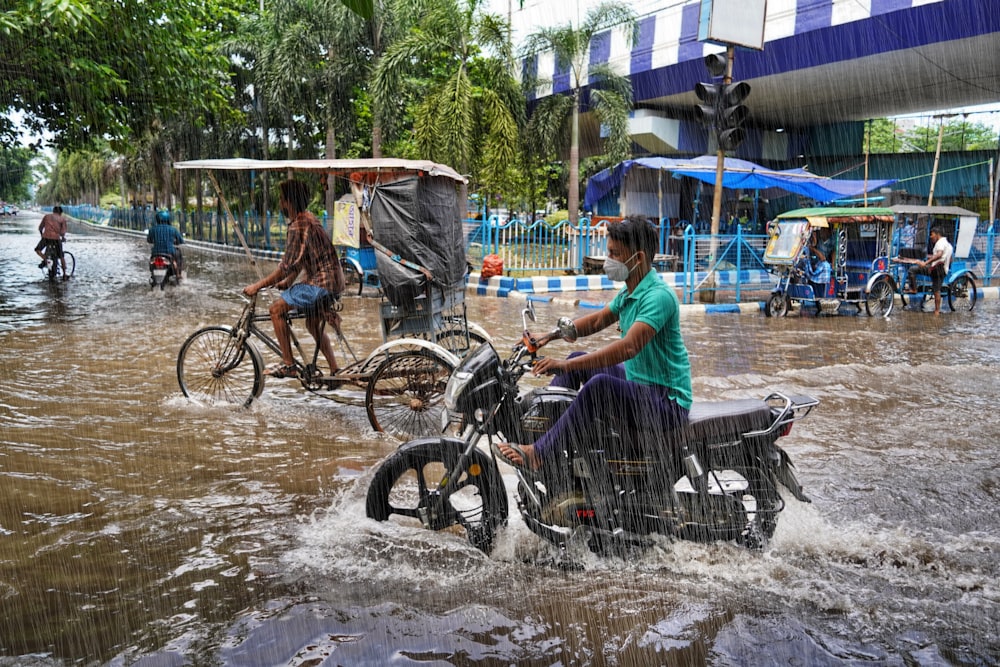 people riding bicycles through a flooded street