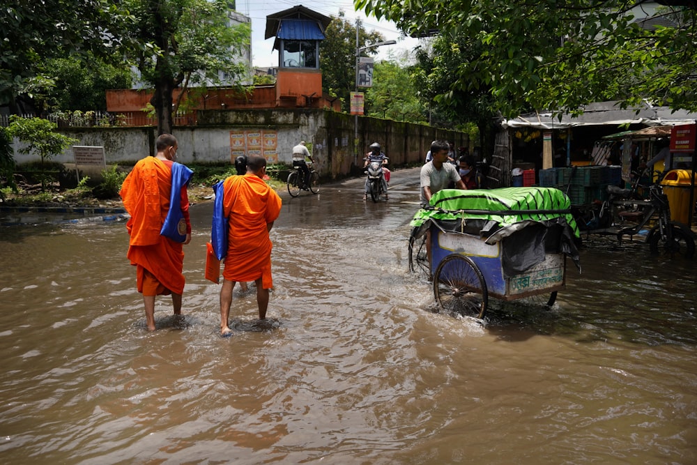 a group of men carrying a cart through a flooded street