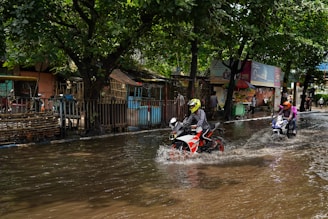 a group of people riding motorcycles through a flooded street