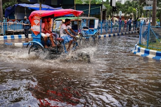people riding on a bike through a flooded street