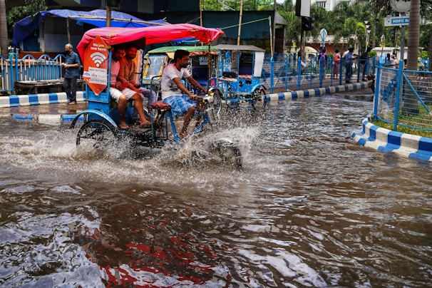 people riding on a bike through a flooded street
