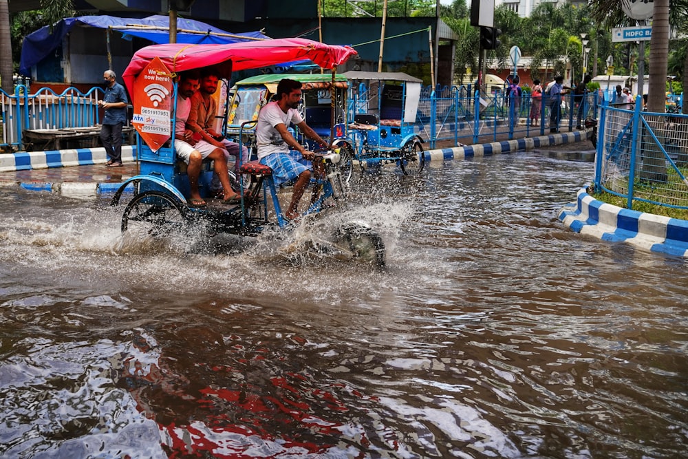people riding on a bike through a flooded street