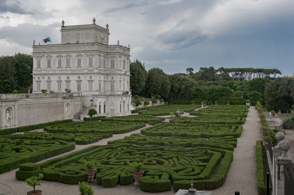 a large white building with a large garden in front of it